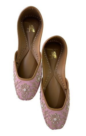 Pair of pink embroidered shoes with brown soles on a white background