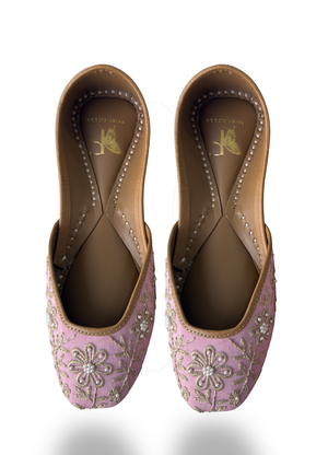 Pair of pink embroidered shoes with floral patterns on a white background